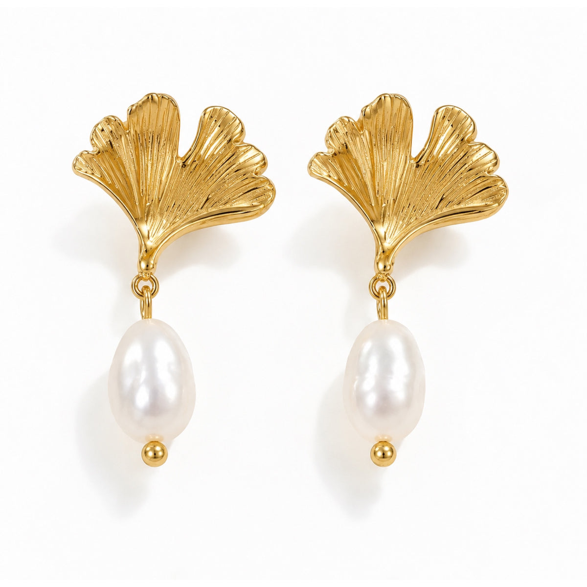 Par de aretes con hojas de ginkgo en tono dorado y perlas cultivadas de agua dulce ovaladas color marfil, sobre fondo blanco.