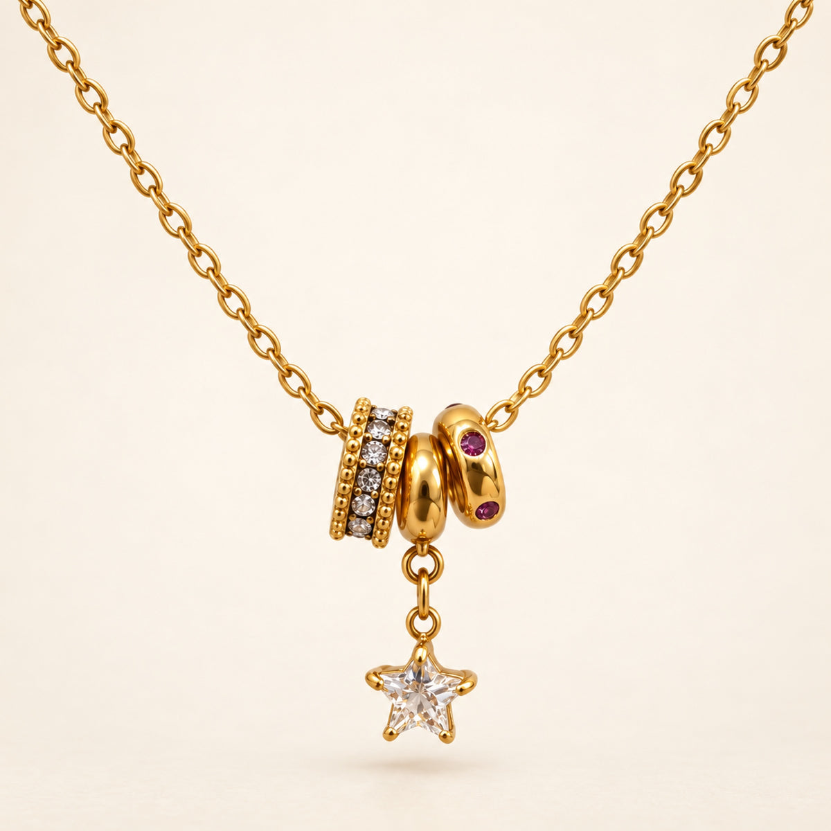 Collar dorado con estrella colgante, tres aros decorativos y piedras transparentes y rojo violáceo. Un detalle especial para tus looks de día o noche.

