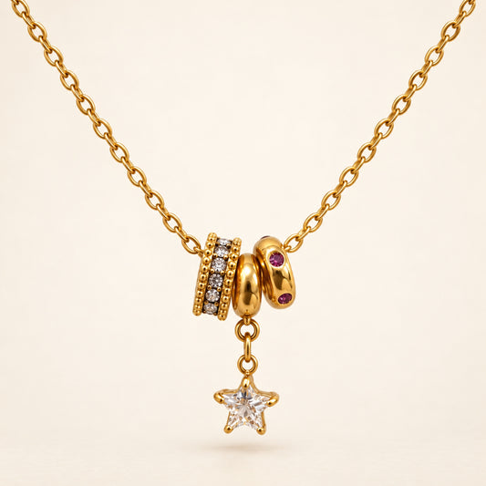 Collar dorado con estrella colgante, tres aros decorativos y piedras transparentes y rojo violáceo. Un detalle especial para tus looks de día o noche.

