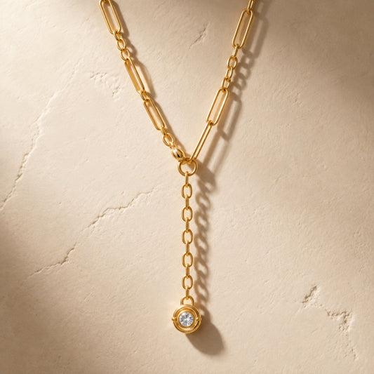 Collar dorado en Y con eslabones alargados y ovalados, aro central y dije circular con una zirconia redonda.

