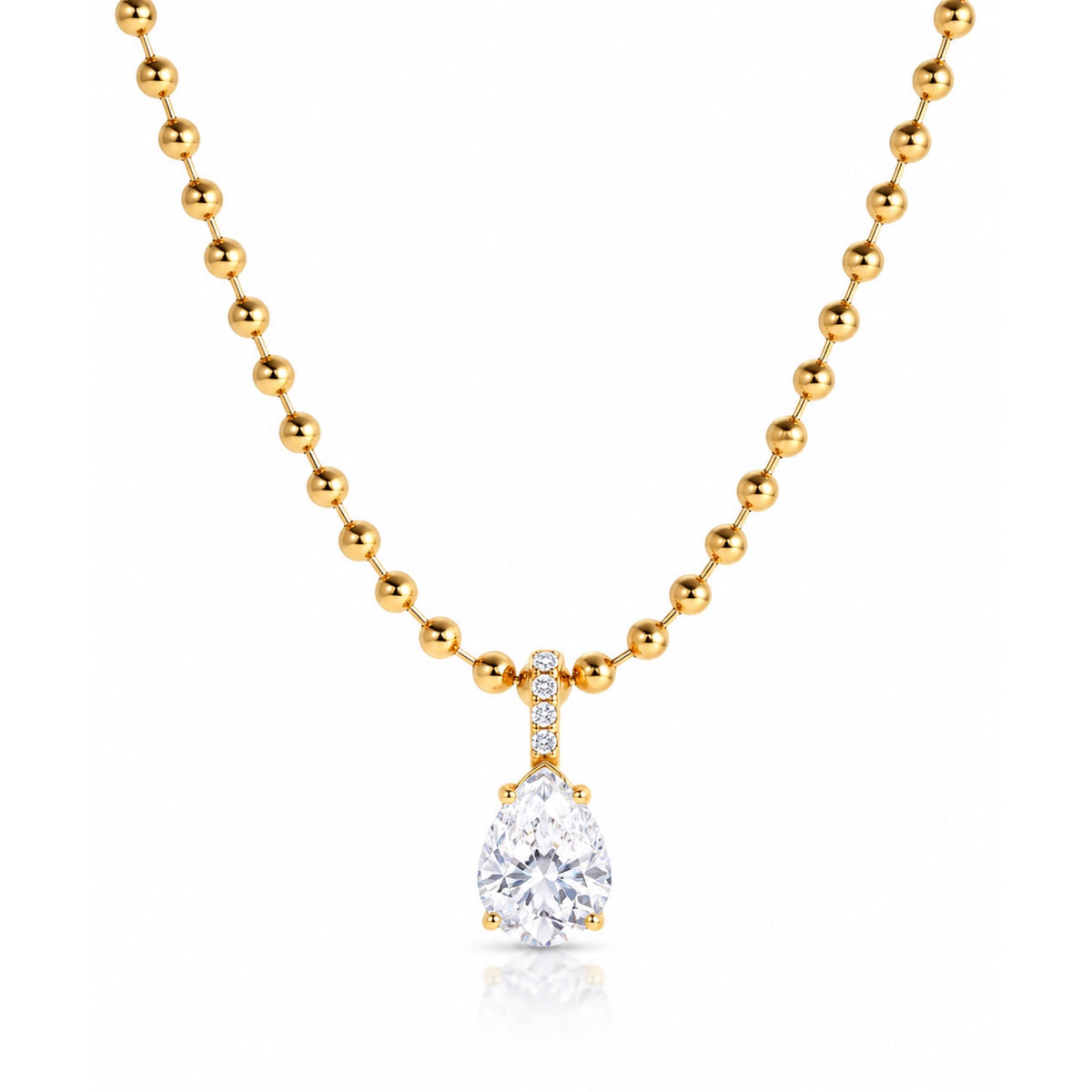 Collar en tono dorado con cadena de bolitas y dije de zirconia transparente en forma de gota, sobre fondo blanco.