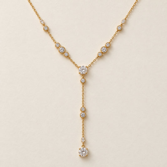 Collar dorado en Y con zirconia central redonda, piedras redondas y alargadas, y cadena colgante terminada en una zirconia redonda.