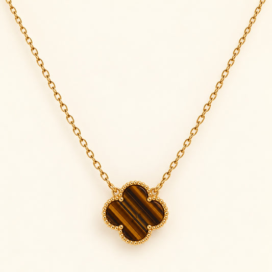 Collar dorado con trébol de cuatro hojas en tonos café y dorados, franjas diagonales y borde de pequeñas cuentas.