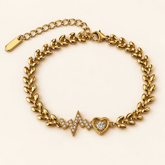 Pulsera dorada con eslabones de hojas, línea de latido con zirconias, corazón con piedra central y cadena de extensión.