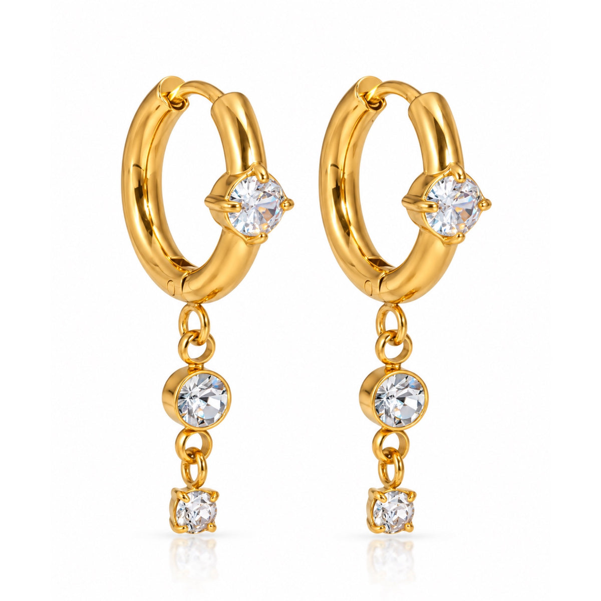 Par de aretes de argolla en tono dorado, cada uno con una zirconia frontal y dos zirconias redondas colgantes, sobre fondo blanco.