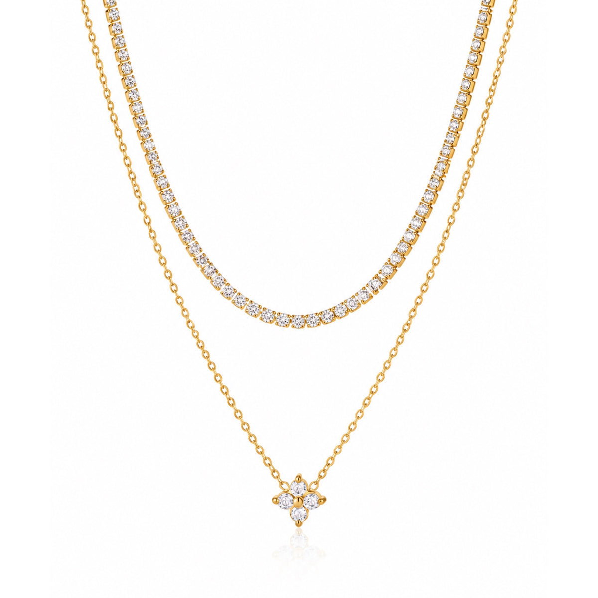 Collar de doble capa en tono dorado con una fila de zirconias y una cadena fina con dije de flor de cuatro pétalos, sobre fondo blanco.